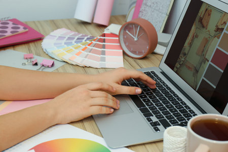 Female designer working at wooden table indoors, closeupの写真素材