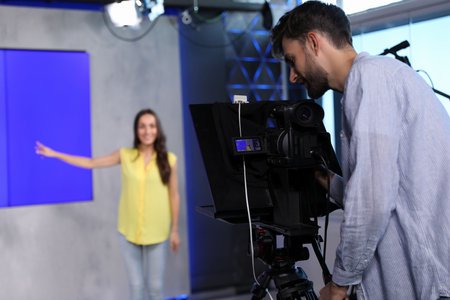 Professional video camera operator and presenter working in studioの写真素材
