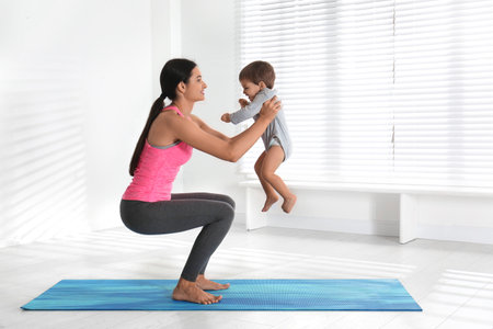 Young woman doing exercise with her son indoors. home fitnessの写真素材