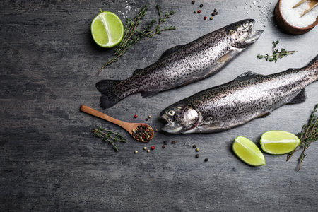 Flat lay composition with raw cutthroat trout fish on gray table