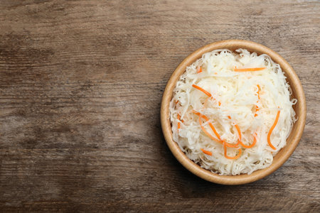 Tasty fermented cabbage on wooden table, top view. Space for textの写真素材