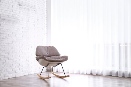 Comfortable rocking chair near white brick wall. Space for textの写真素材