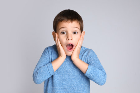 Portrait of emotional little boy on light gray backgroundの写真素材