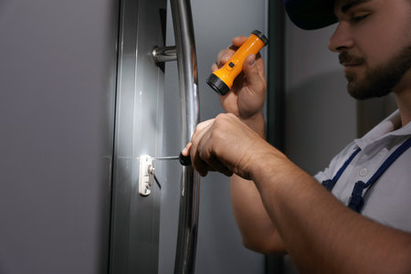 Repairman with flashlight fixing door lock, closeupの写真素材