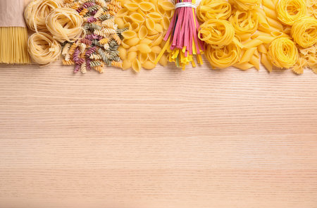 Different types of pasta on wooden table, flat lay. Space for textの写真素材