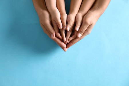 Mother holding hands with her children on blue background, top view. happy familyの写真素材