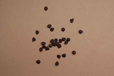 Delicious chocolate chips on brown background, top view