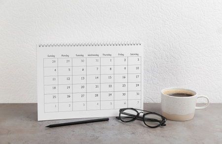Calendar, glasses, pencil and cup of coffee on gray stone tableの写真素材