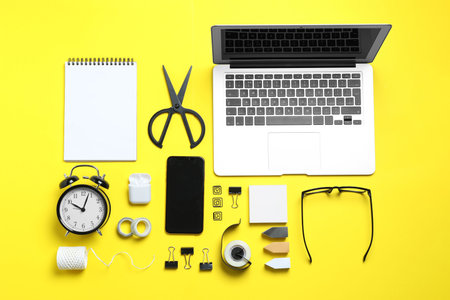 Flat lay composition with laptop, smartphone and stationery on yellow background. Designer's workplaceの写真素材