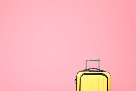 Stylish yellow suitcase on pink background. Space for textの写真素材