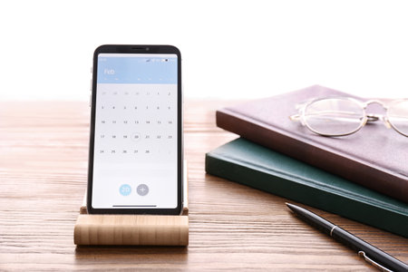 Smartphone with calendar app on wooden table
