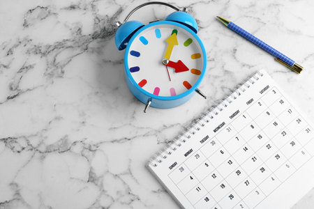 Calendar, pen and alarm clock on white marble background,の写真素材