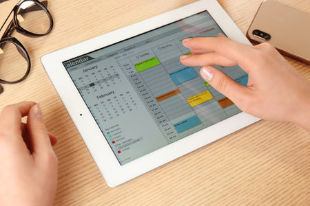 Woman using calendar app on tablet in office, closeupの写真素材