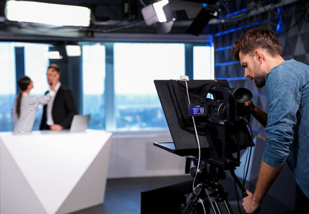 Professional video camera operator working in studio. News broadcastingの写真素材