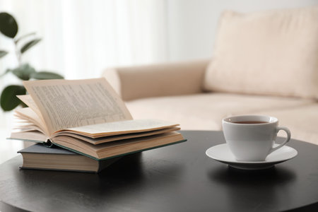 Books and cup of tea on table near modern sofa indoors. home interiorの写真素材