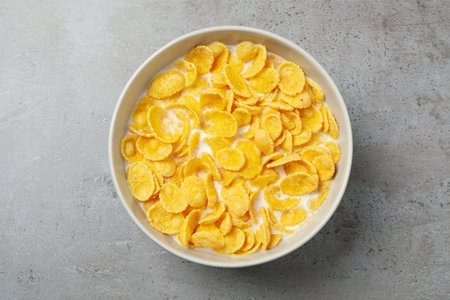 Tasty crispy corn flakes with milk on light gray table, top view