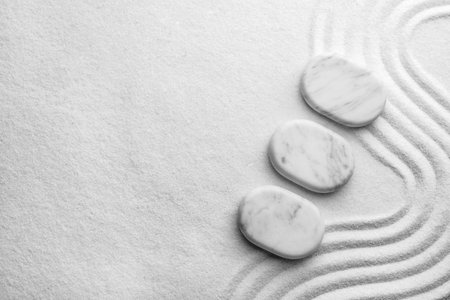 Top view of white stones on sand with pattern, space for text. Zen, meditation, harmony
