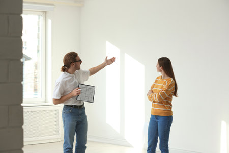 Professional interior designer consulting woman in empty apartmentの写真素材