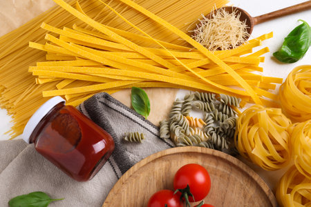 Flat lay composition with different types of pasta on white tableの写真素材