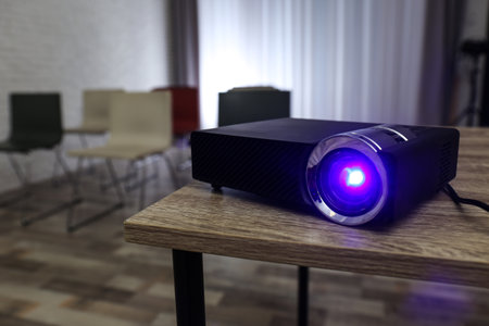 Modern video projector on wooden table in conference roomの写真素材