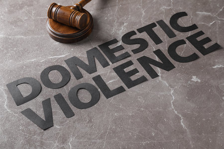 Words DOMESTIC VIOLENCE and gavel on gray marble table