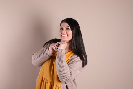 Beautiful overweight woman posing on beige background. plus size model