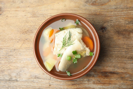 Delicious fish soup in bowl on wooden table, top viewの写真素材