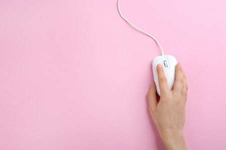 Woman using modern wired optical mouse on pink background, top view. Space for textの写真素材