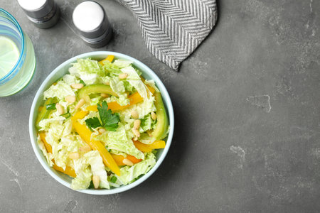 Bowl of fresh cabbage salad with bell pepper on gray table, top view. Space for textの写真素材