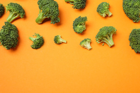 Fresh tasty broccoli on orange background, flat lay. Space for textの写真素材