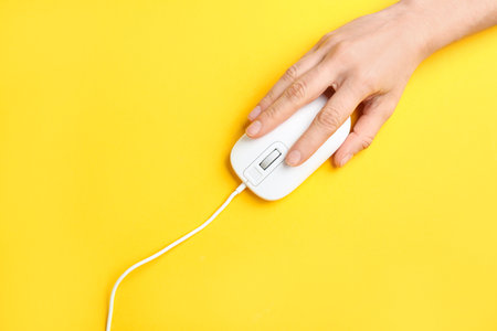 Woman using modern wired optical mouse on yellow background, top viewの写真素材