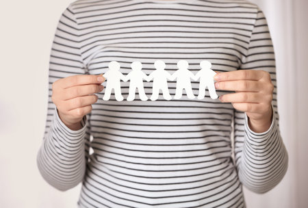 Woman holding paper people chain indoors, closeup. unity conceptの写真素材