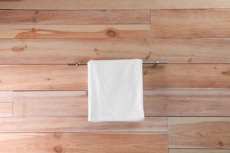 Rack with clean soft towel on wooden wallの写真素材