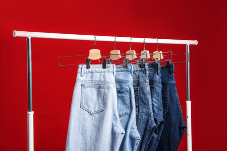 Rack with different jeans on red backgroundの写真素材