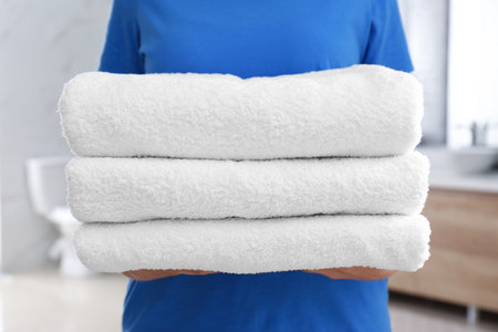 Woman holding fresh towels in bathroom, closeupの写真素材