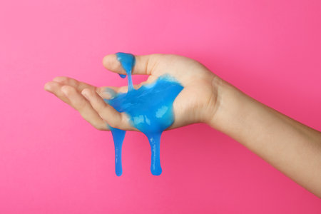 Woman playing with blue slime on pink background, closeup. antistress toyの写真素材