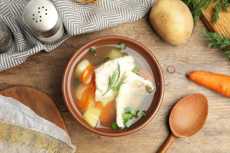 Delicious fish soup served on wooden table, flat layの写真素材
