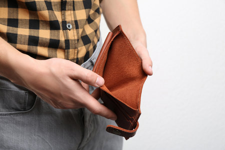 Man showing empty wallet on light background, closeup