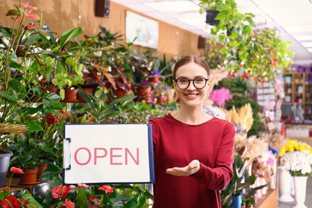 Female business owner holding OPEN sign in flower shop