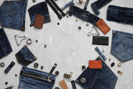 Frame made of garment accessories and cutting details for jeans on gray marble background, flat lay....
