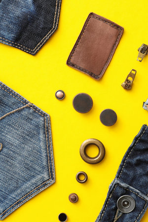 Flat lay composition with garment accessories and cutting details for jeans on yellow backgroundの写真素材
