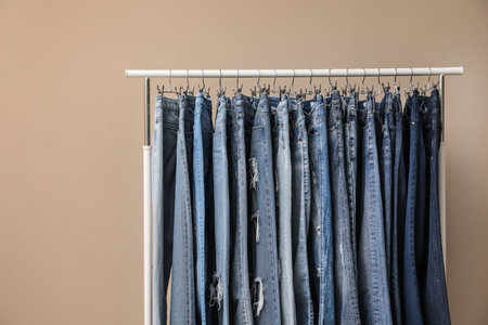 Rack with stylish jeans on beige backgroundの写真素材