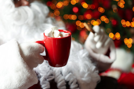 Santa Claus with hot drink and cookie against blurred Christmas lights, closeupの写真素材
