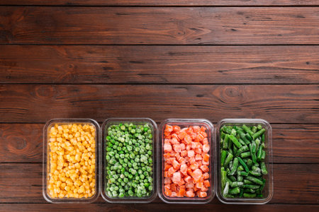 Different frozen vegetables on wooden table, flat lay. Space for textの写真素材