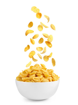 Tasty crispy corn flakes falling into bowl on white background