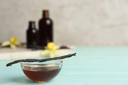 Aromatic homemade vanilla extract on light blue wooden table. Space for text