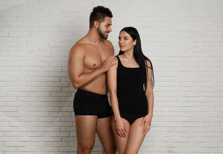 Young couple in black underwear near white brick wallの写真素材