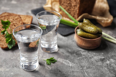 Cold Russian vodka with snacks on gray table, closeup