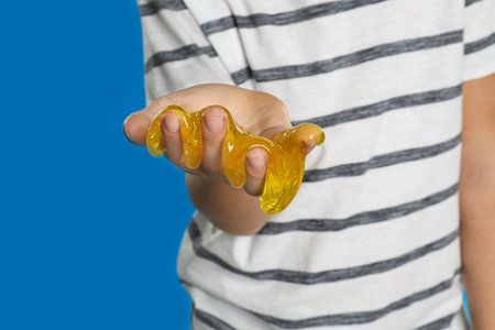 Little boy with slime on blue background, closeup