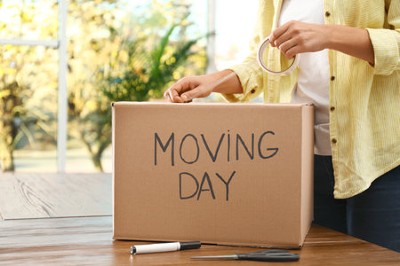Woman packing box with words MOVING DAY at wooden table, closeupの写真素材